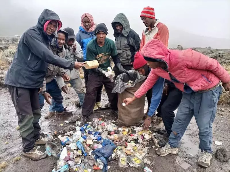 TK staff volunteering to support a Green Porter with rubbish collection having completed their camp duties.
