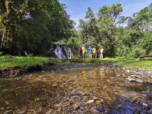 Relaxing at the small waterfall on a 1-day Pre-Kilimanjaro acclimatisation trek on Mount Meru's lower slopes